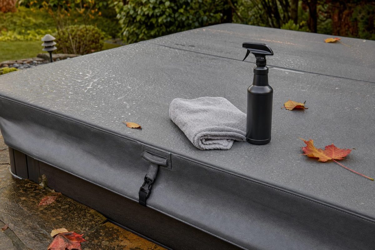 Soft cloth and spray bottle of cover cleaner on the grey vinyl of a hot tub cover