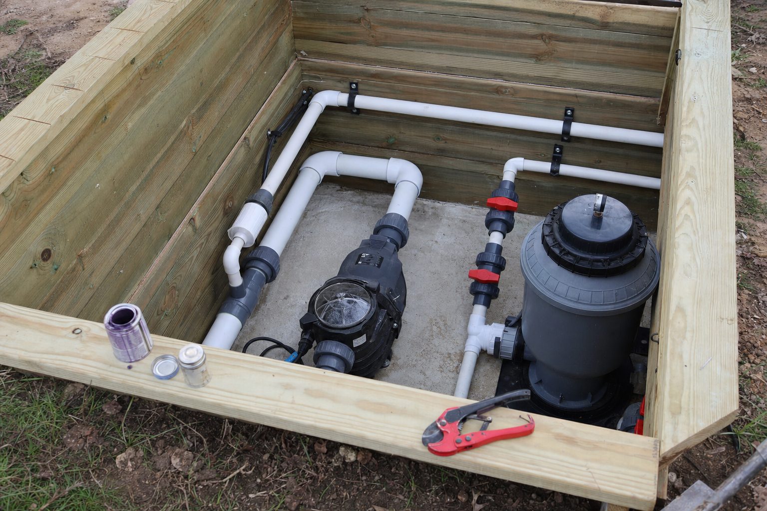 DIY hot tub control room under construction with PVC pipework, valves, a pump and a filter being dry-fitted before gluing