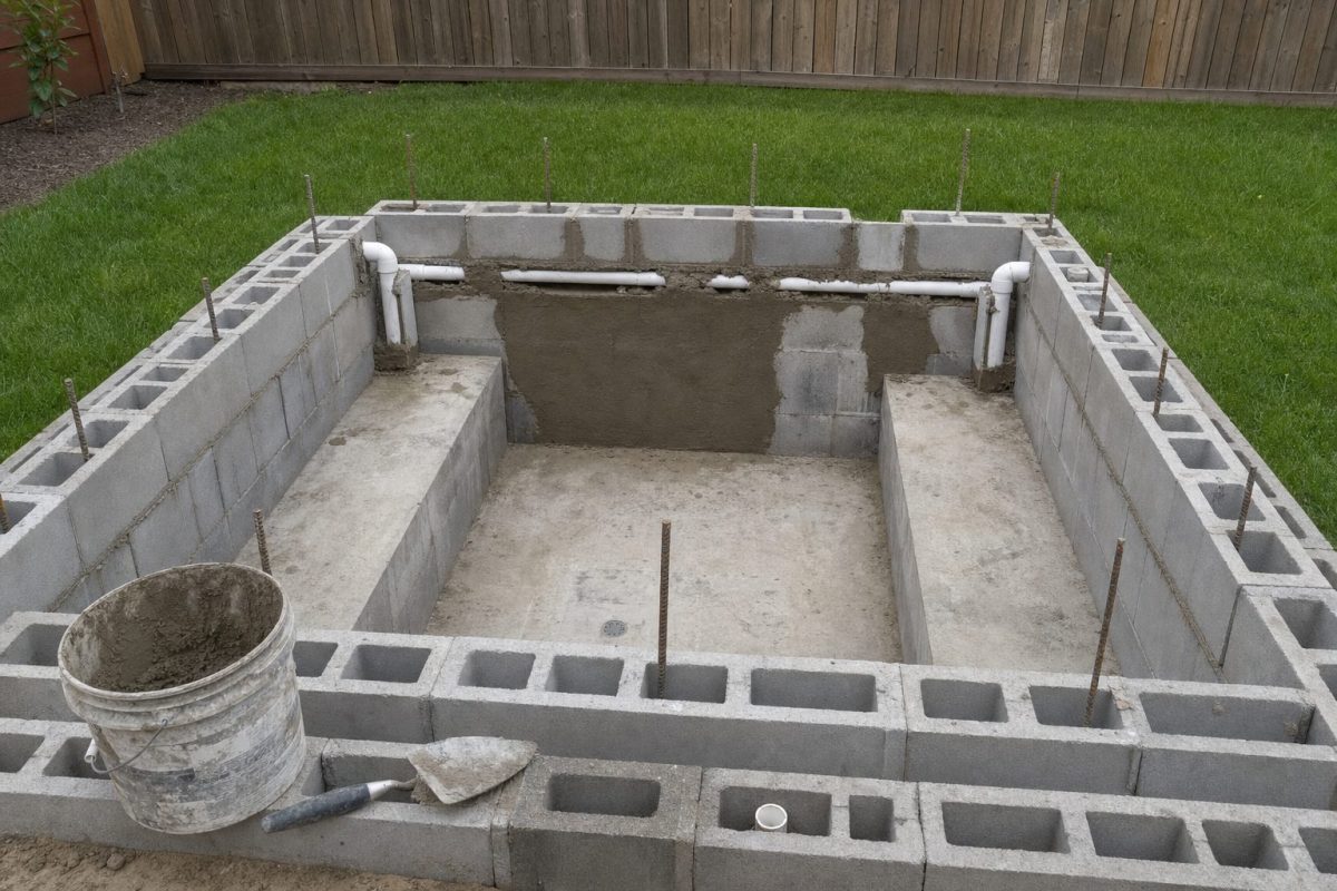 Cinder block hot tub under construction with reinforced block walls and seats