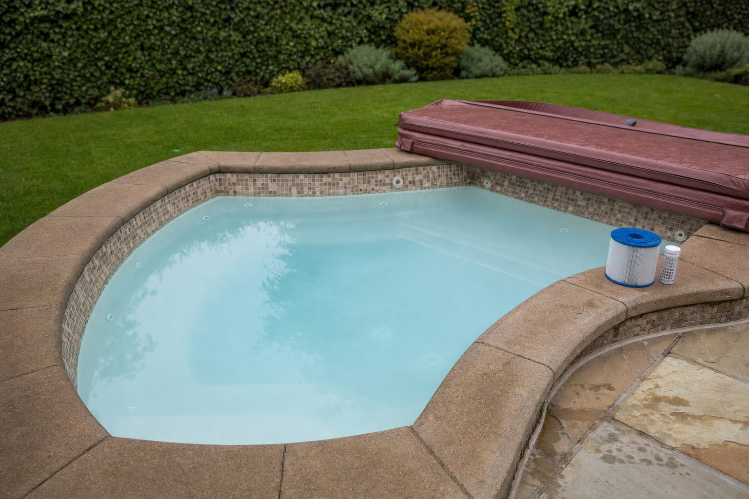 Cloudy, milky water in a tiled garden hot tub with the cover folded back