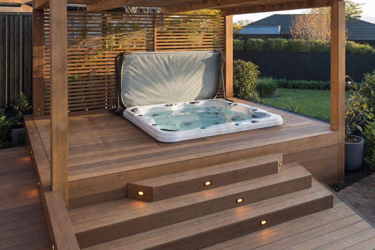 Hot tub recessed into a multi-level timber deck with steps, lighting and privacy screening