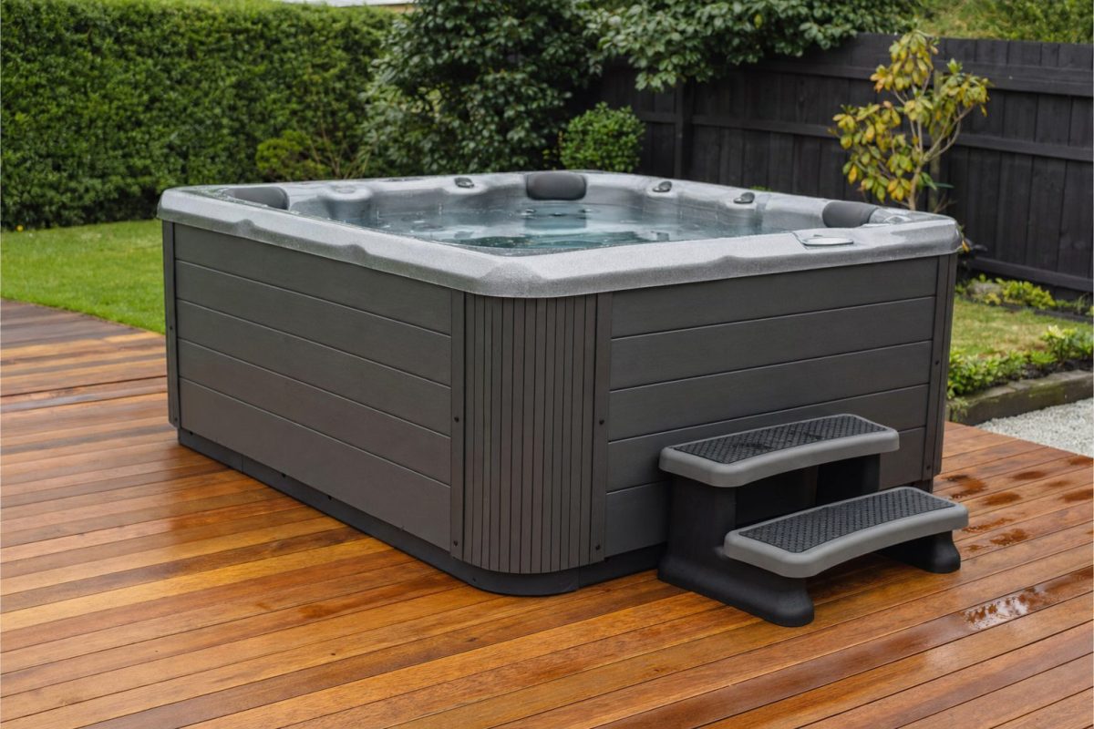 Hot tub with a set of non-slip steps beside a wooden deck
