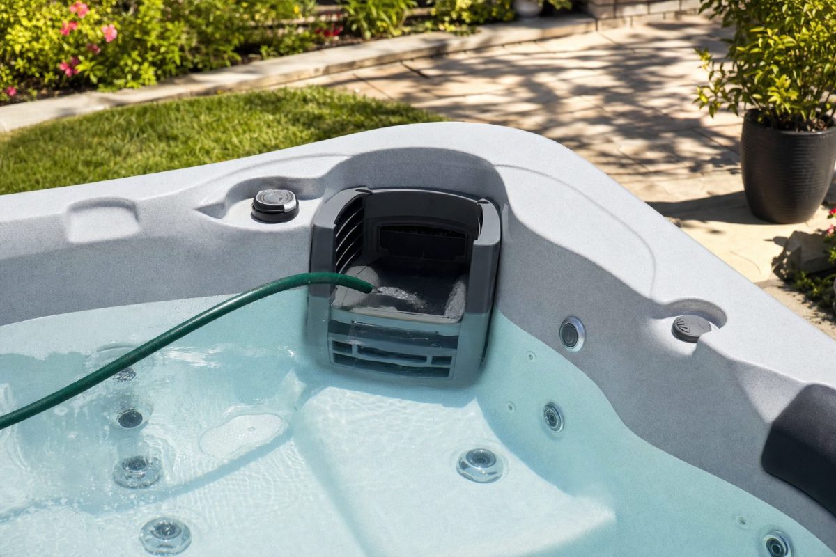 Garden hose filling a hot tub through the filter housing with clear water