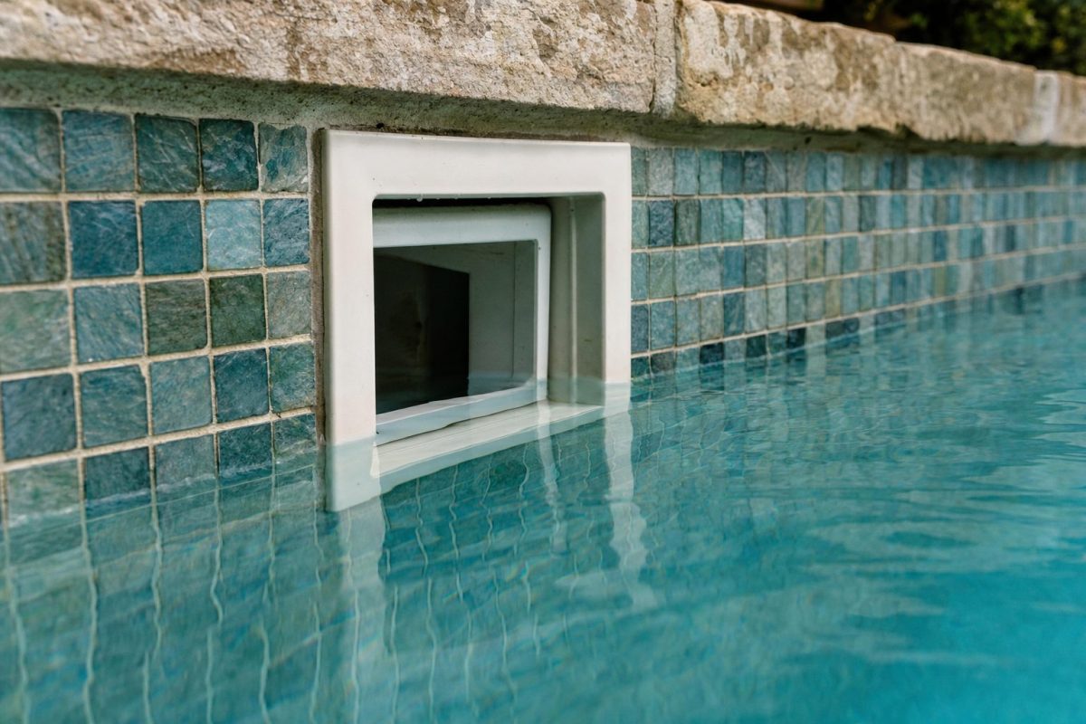 Skimmer set into the tiled wall of a DIY plunge pool at the waterline