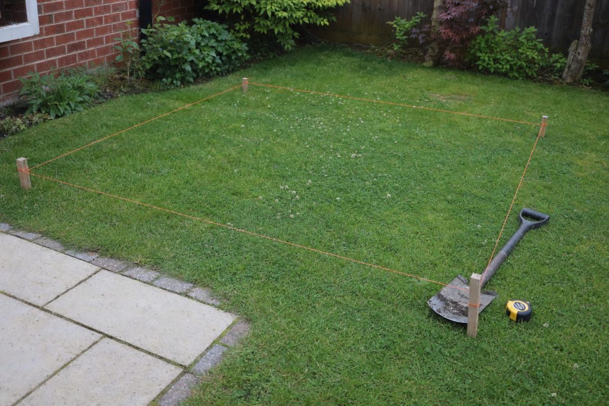 Back garden marked out with string lines and pegs ready for a DIY hot tub build