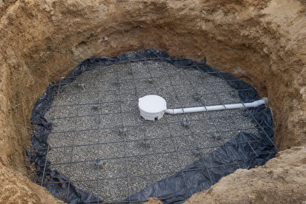 Main drain with hydrostatic relief valve set on a gravel sub-base among steel reinforcement, ready for the concrete floor of an in-ground hot tub